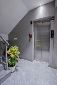 a metal elevator door in a building with a potted plant at The Bay Suites - Salt Lake in kolkata