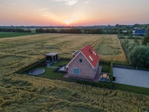 a house in a field with the sunset in the background at NIEUW Landzicht in Serooskerke