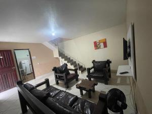 a living room with a couch and chairs and a staircase at Pousada Recanto Penedo in Penedo