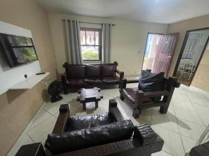a living room with leather couches and chairs at Pousada Recanto Penedo in Penedo