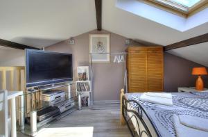 a bedroom with a bed and a flat screen tv at Chez Laurence et Thomas in Cercié