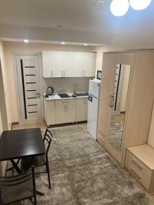 a small kitchen with a table and a refrigerator at Radugawest2 in Koshkolʼ