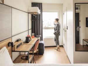 a man standing in a hotel room looking out the window at ibis Antwerpen Centrum in Antwerp