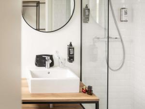 a bathroom with a sink and a shower with a mirror at ibis Antwerpen Centrum in Antwerp