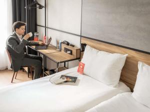 a man sitting at a desk with a cup of coffee at ibis Antwerpen Centrum in Antwerp +104 photos