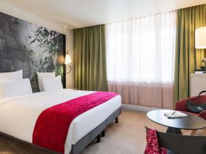 a hotel room with a large bed with a red blanket at Mercure Paris La Défense in Courbevoie