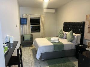 a bedroom with a bed and a desk and a chair at Skyfly Bed & Breakfast in Manzini