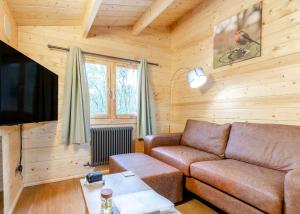 a living room with a brown couch and a tv at Quarry Walk Lodges in Cheadle