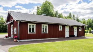 a red and white building with a grass yard at Norbergs Camping in Norberg