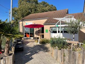 a building with a red umbrella and a fence at Camping Beausejour Sergines in Sergines