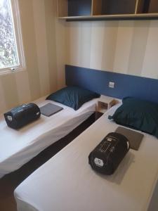 two beds in a room with a laptop and a bag at Camping Beausejour Sergines in Sergines