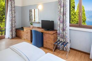 a bedroom with a desk with a television and windows at Park Hotel Jolanda in San Zeno di Montagna