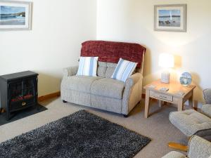 a living room with a chair and a stove at Eagle Cottage in Culkein