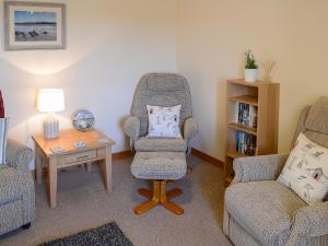 a living room with a chair and a table at Eagle Cottage in Culkein