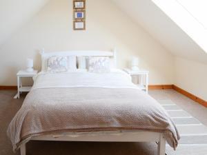 a bedroom with a white bed with two white tables at Eagle Cottage in Culkein +4 photos