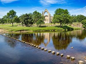 a view of a church and a river with logs in the water at Rosemount Cottage in Salterforth