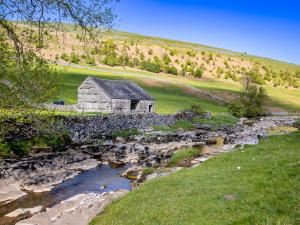 an old stone barn sits next to a river at Rosemount Cottage in Salterforth +11 photos