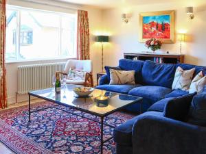 a living room with a blue couch and a table at Stokewood Annexe in Freshford