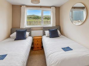 two beds in a small room with a window at Y Gorlan - Uk6403 in Llanllechid