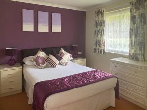 a bedroom with a bed with purple walls and windows at Eden - B6526 in Saint Cleer +7 photos