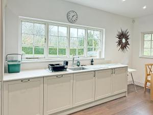 a kitchen with a sink and a clock on the wall at Glanusk Lodge - Uk46654 in Crickhowell