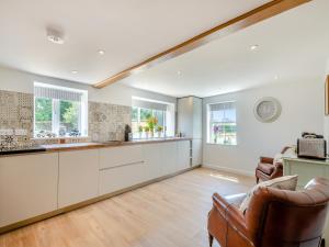 an empty kitchen with white cabinets and windows at Manor Cottage in Longham