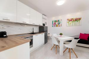 a kitchen with white cabinets and a white table and chairs at Apartments Jana in Krk