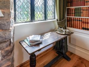 a table in a room with a window and books at The Tower - Uk46652 in Crickhowell