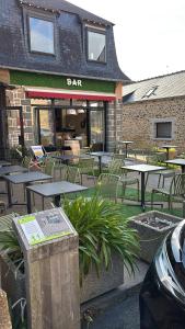 a bar with tables and chairs in front of a building at Au bon saint Nicolas in Hillion