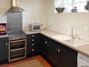 a kitchen with a microwave and a sink at The Library - Uk46649 in Crickhowell