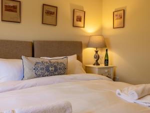 a bedroom with a white bed with a lamp and a bottle of wine at The Library - Uk46649 in Crickhowell