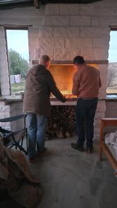 Zwei Männer stehen vor einem steinernen Kamin in der Unterkunft Van Wyks Hartshuis in Sutherland