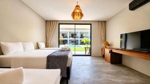 a bedroom with two beds and a flat screen tv at Luau Hotel in Flecheiras