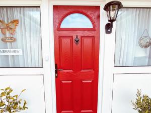 a red door with a window on a white house at Merriview in Germoe +15 photos