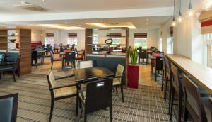 a restaurant with tables and chairs and a bar at Holiday Inn Express Bristol Filton by IHG in Bristol