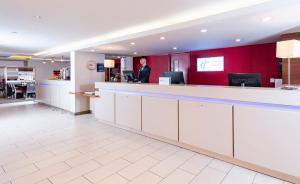 a man is standing at the reception desk of a hospital at Holiday Inn Express Bristol Filton by IHG in Bristol