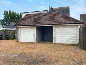 a garage with two garage doors and a fence at Dory in Rye
