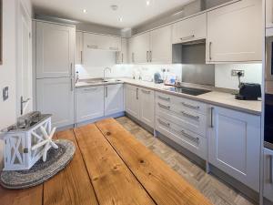 a kitchen with white cabinets and a wooden floor at Dory in Rye +7 photos
