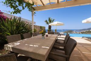 a wooden table and chairs on a patio with a pool at Villa Yakamoz in Kalkan