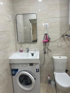 a bathroom with a washing machine and a sink at Radugawest2 in Koshkolʼ
