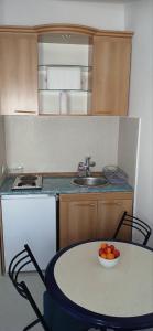 a kitchen with a table with a bowl of fruit on it at Apartman Vuk in Budva +5 photos