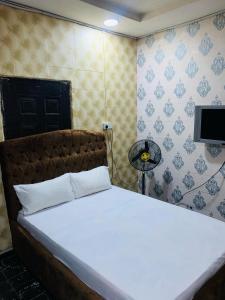 a bedroom with a large white bed with a tv on the wall at Lazeto Hotel & Resort in Zokoja +1 photo