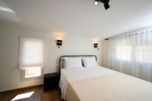a bedroom with a white bed and two windows at Oropion Rental houses in Néa Palátia