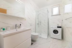 a white bathroom with a toilet and a washing machine at Apartments Jana in Krk