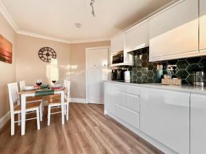a kitchen with white cabinets and a table and chairs at Treetops in Baildon