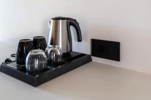 a coffee pot on a black tray with three glasses at La Finestra in Nydri