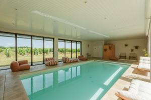 a large swimming pool with chairs and a room with windows at Villa Sarment Oleron in Saint-Pierre-dʼOléron