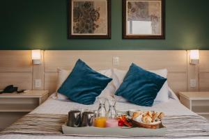 ein Tablett mit Essen auf einem Bett mit blauen Kissen in der Unterkunft Farina Park Hotel in Bento Gonçalves
