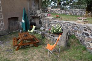 a table and chairs and an umbrella next to a stone wall at Le Refuge de l'Argence in Alpuech +58 photos