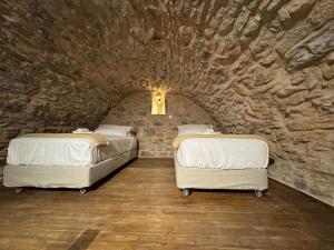 two beds in a room with a stone wall at Casa Di Lithos in Mestá